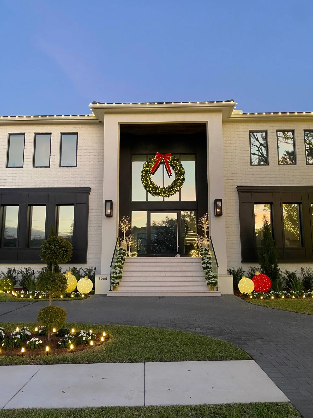 Modern Tampa home ready for Thanksgiving with a lit wreath, warm white roofline and glowing entry